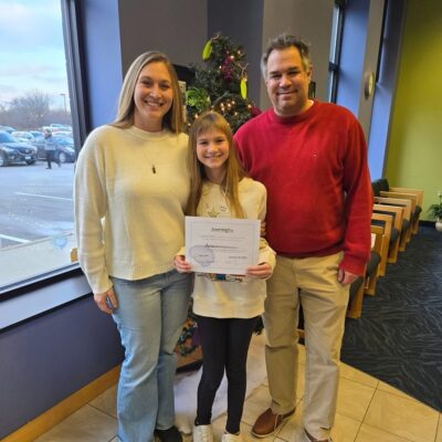 graduate of LearningRx holding certificate with parents