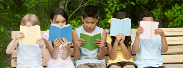 Row of kids sitting on a bench reading books
