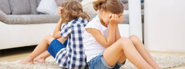 Kids sitting back-to-back in frustration